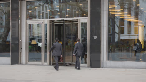 Los-Empresarios-Caminando-Hacia-El-Edificio-De-Oficinas-Con-Puerta-Giratoria-En-Mayfair,-Londres,-Gran-Bretaña.